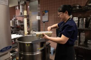 A worker preparing food in a large, clean food preparation area