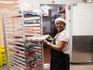 A worker preparing food trays in a refrigerated area