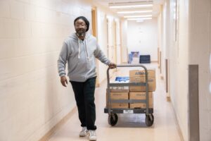 A worker pulling boxes of facial tissue on a cart